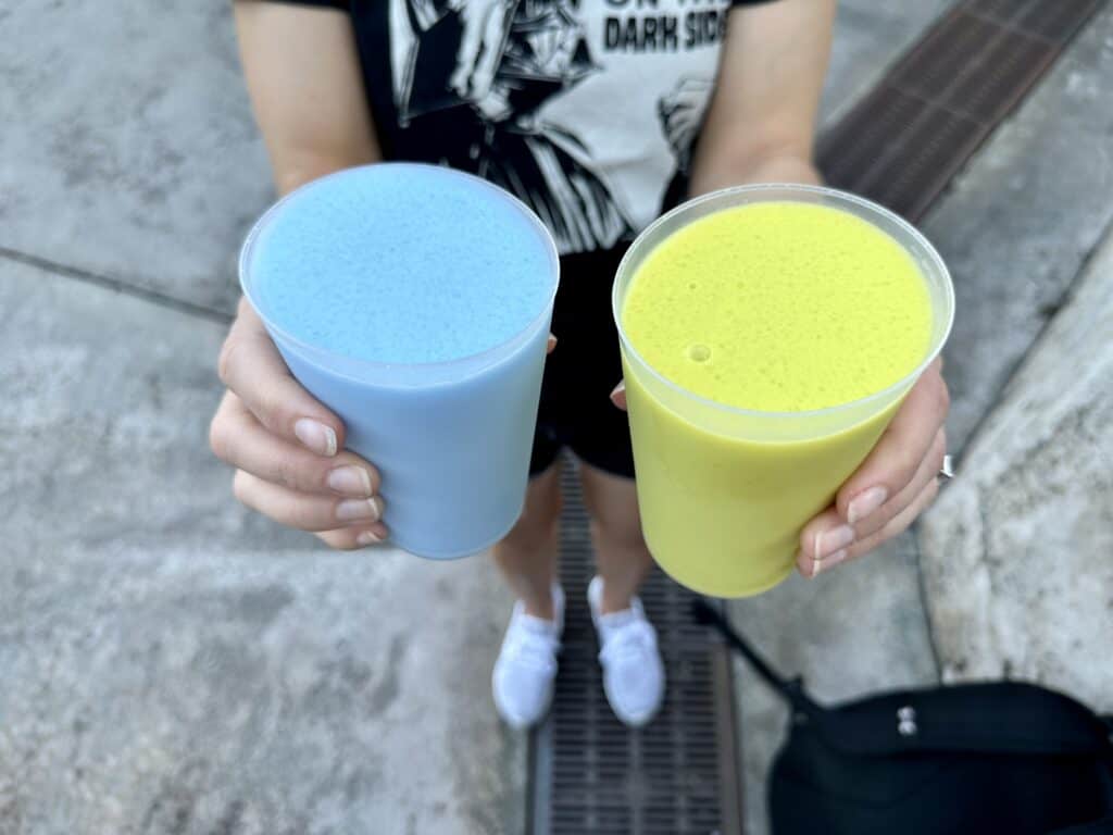 woman holding green milk and blue milk from disney world