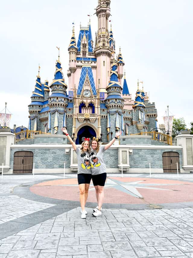 two women in matching disney outfits in front of the disney castle