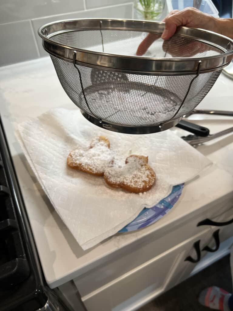 dusting Mickey Mouse shaped beignets