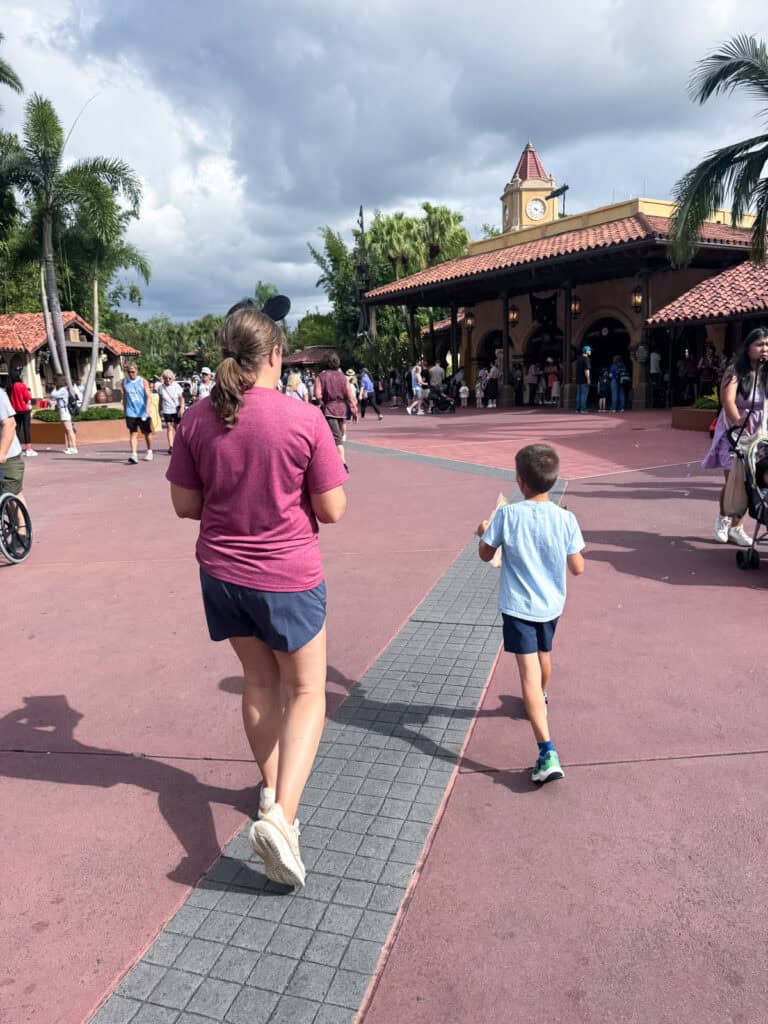 Mom and kid walking in Magic Kingdom doing the treasure hunt.